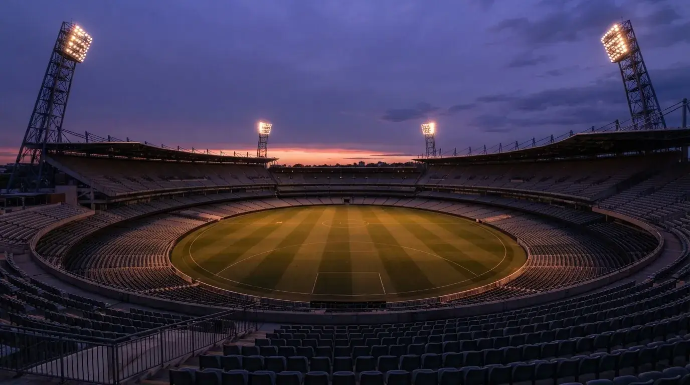 An empty football stadium with floodlight masts at dusk