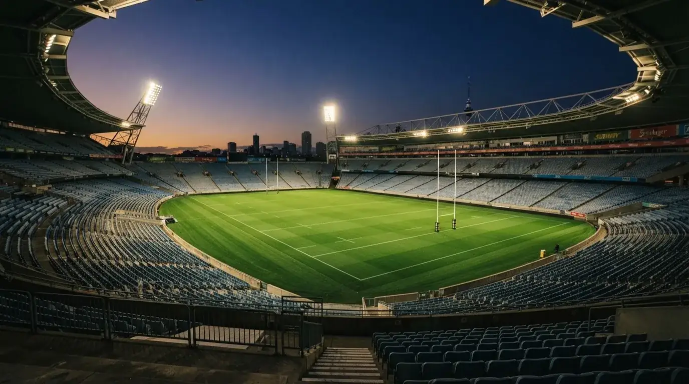An empty football stadium with floodlight masts at dusk