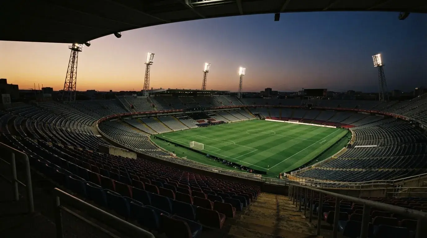 An empty football stadium with floodlight masts at dusk