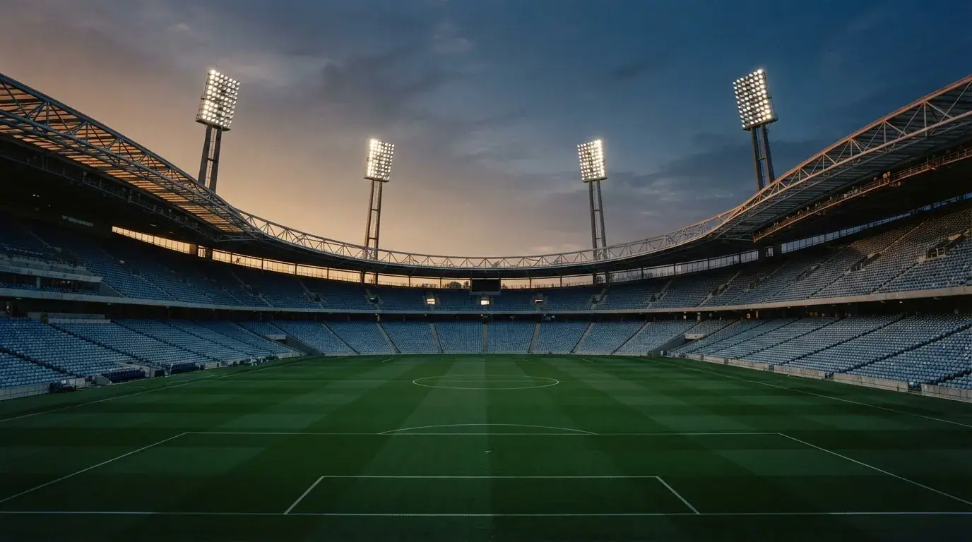An empty football stadium with floodlight masts at dusk