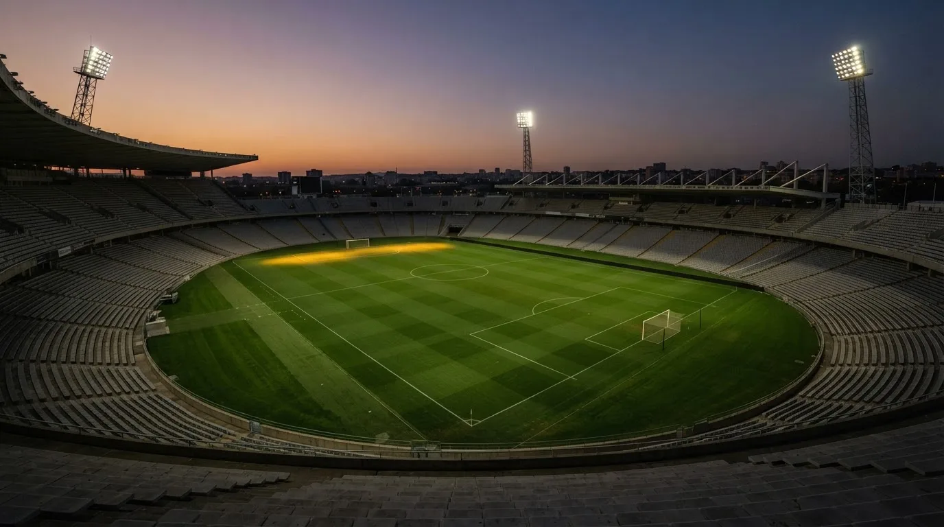 An empty football stadium with floodlight masts at dusk