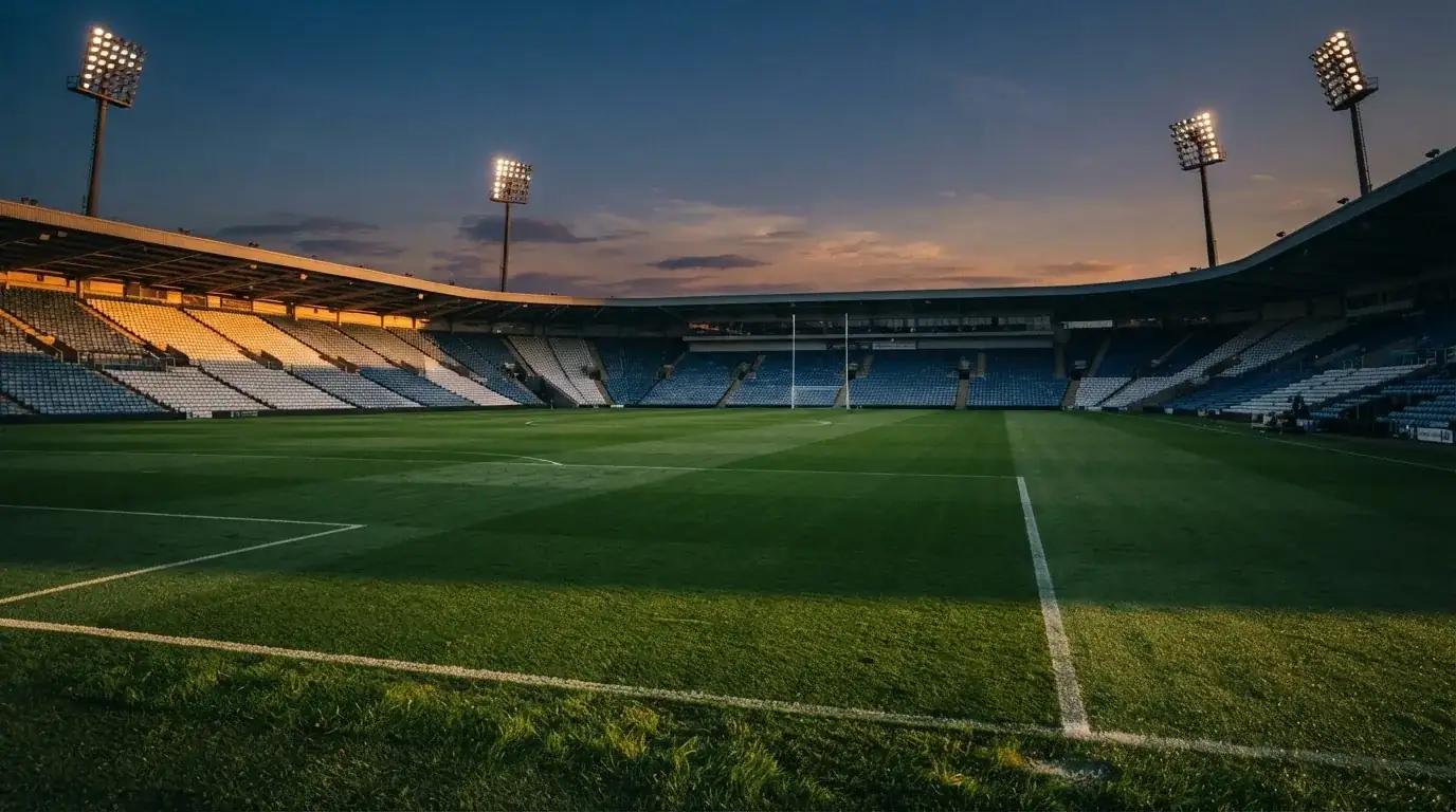 An empty football stadium with floodlight masts at dusk