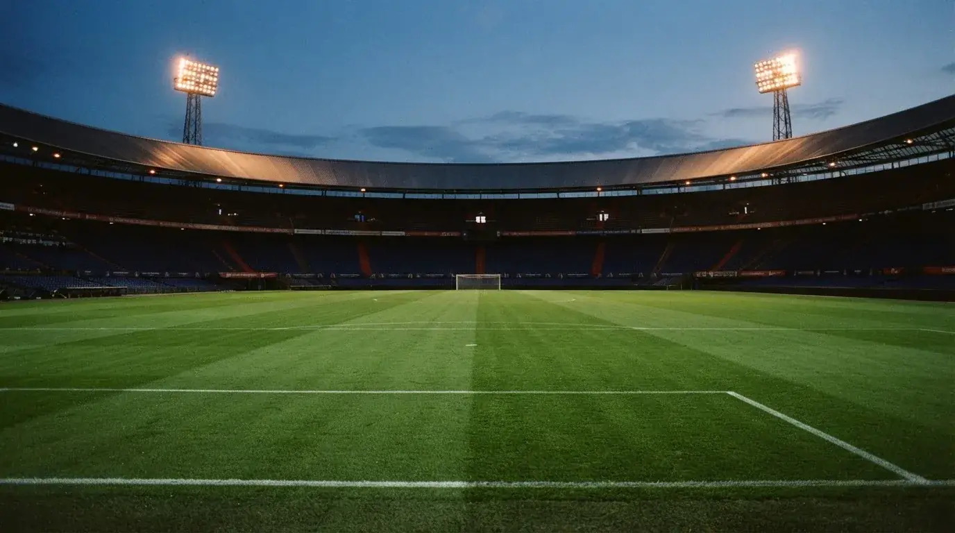 An empty football stadium with floodlight masts at dusk