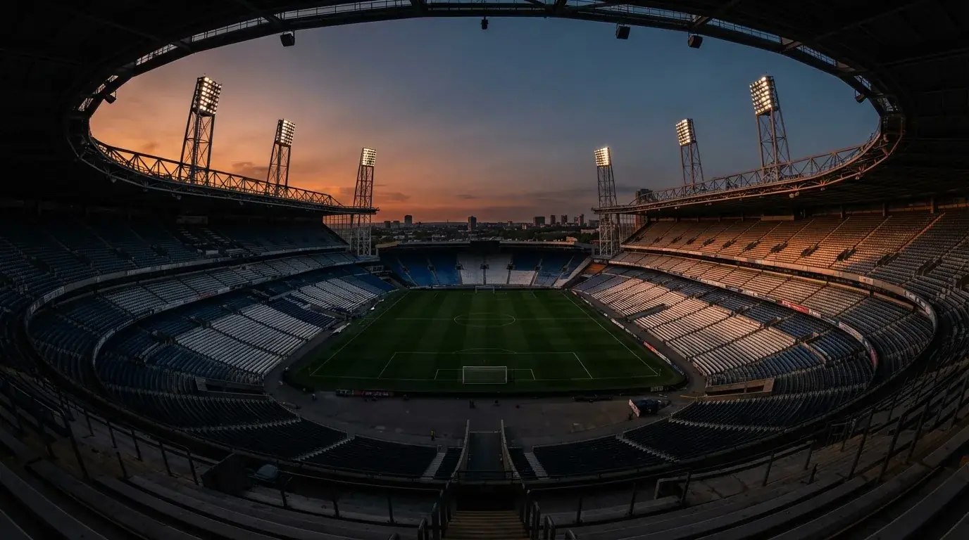 An empty football stadium with floodlight masts at dusk