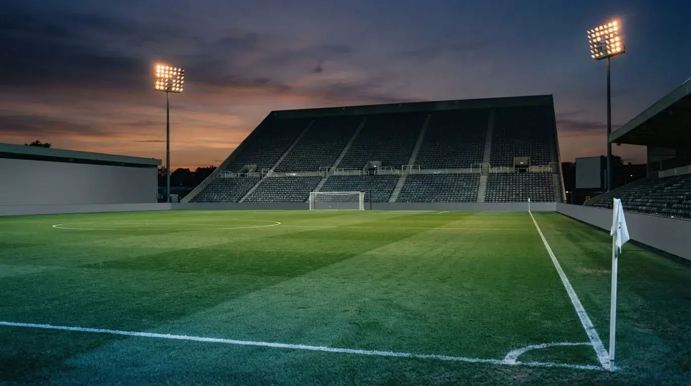 An empty football stadium with floodlight masts at dusk