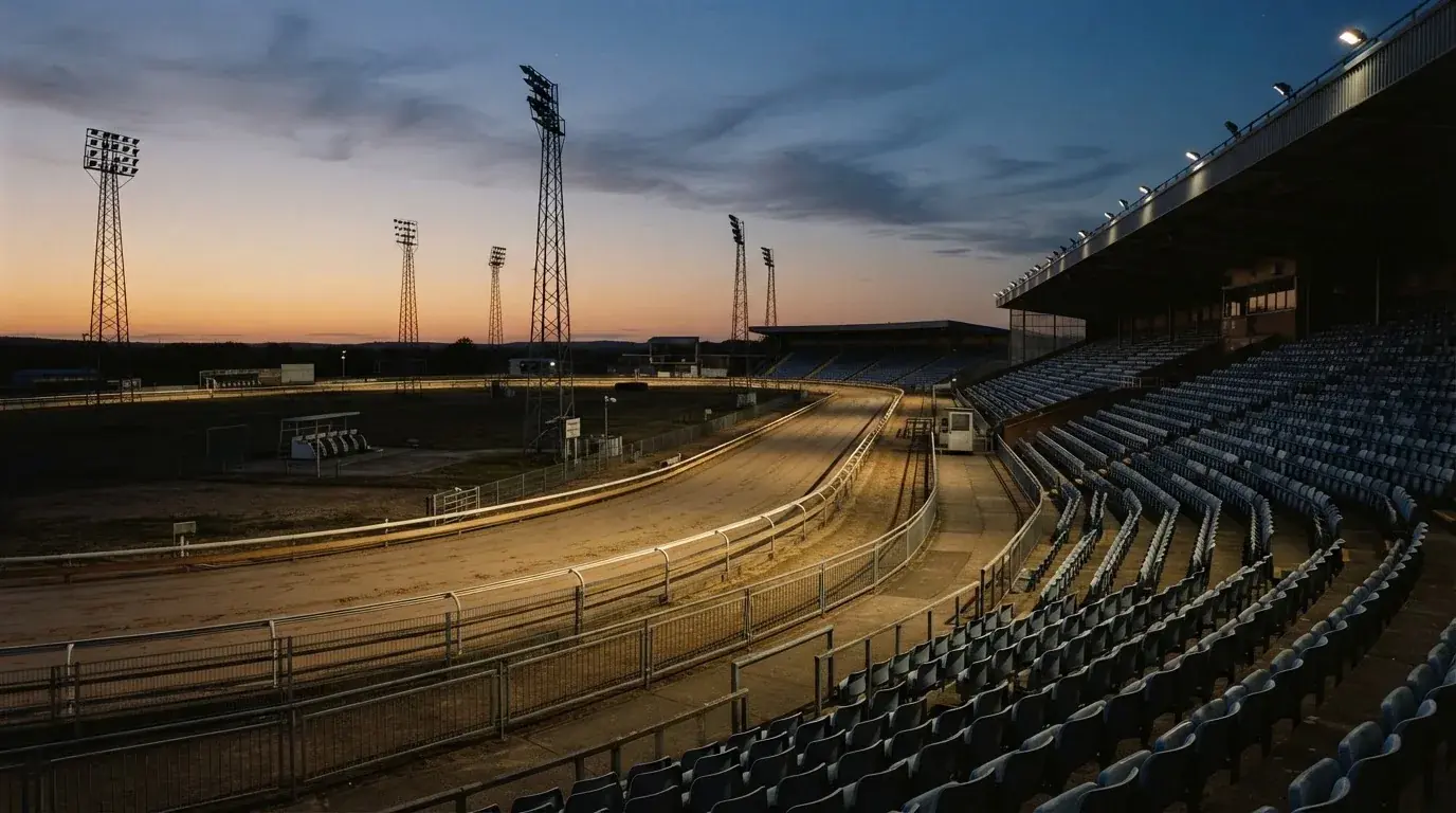 An empty football stadium with floodlight masts at dusk