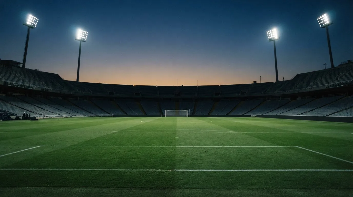 An empty football stadium with floodlight masts at dusk
