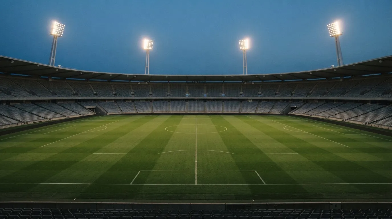 An empty football stadium with floodlight masts at dusk