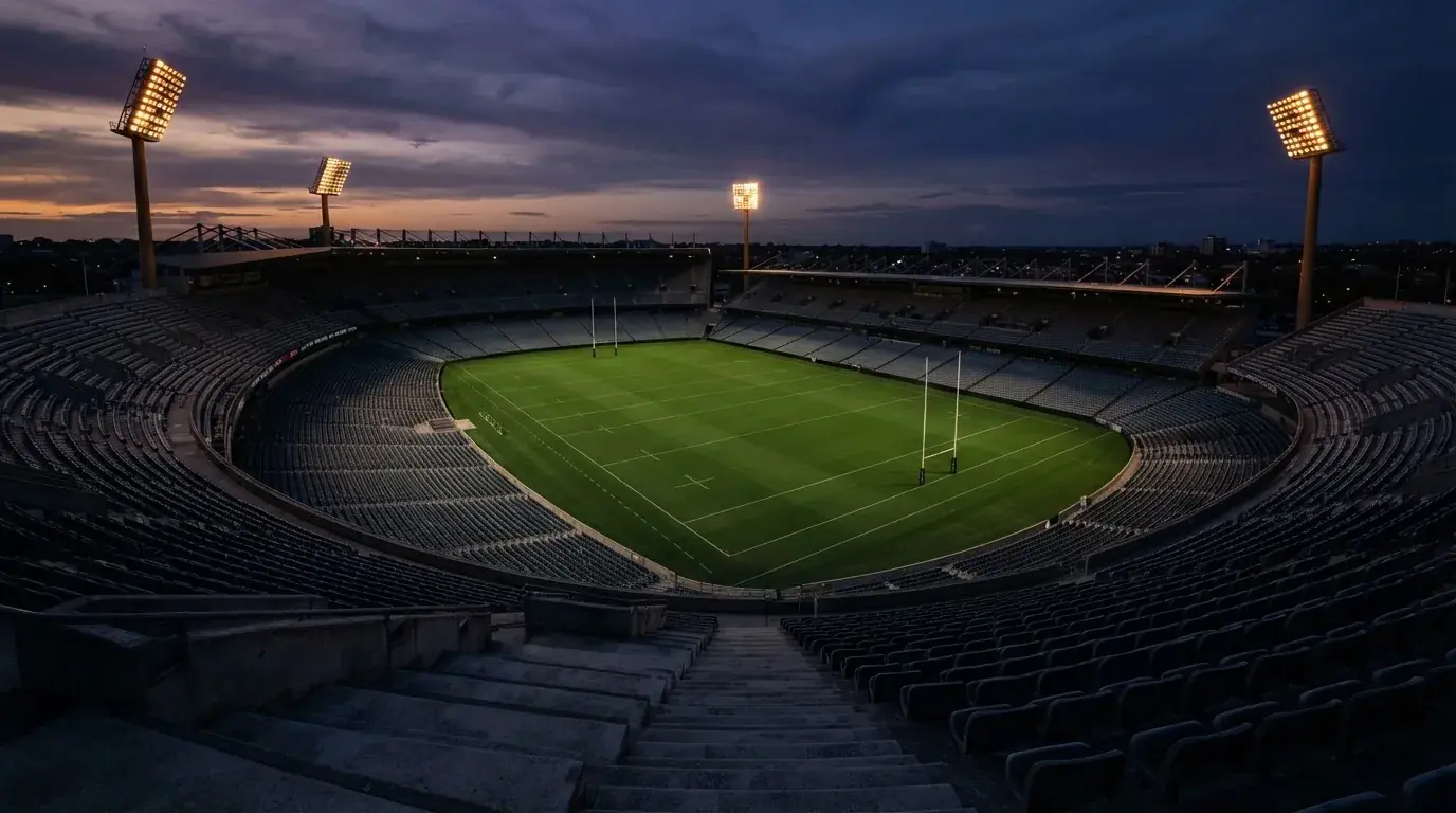 An empty football stadium with floodlight masts at dusk