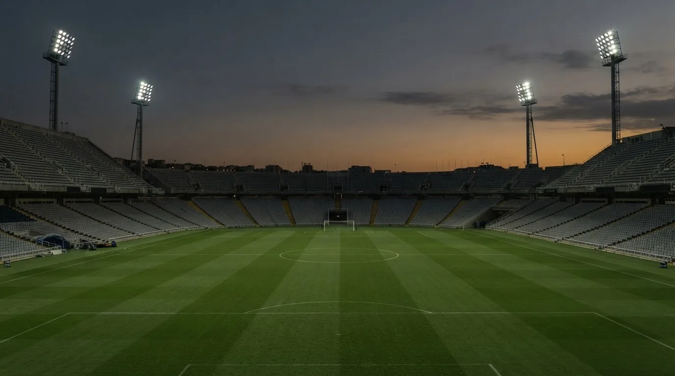 An empty football stadium with floodlight masts at dusk