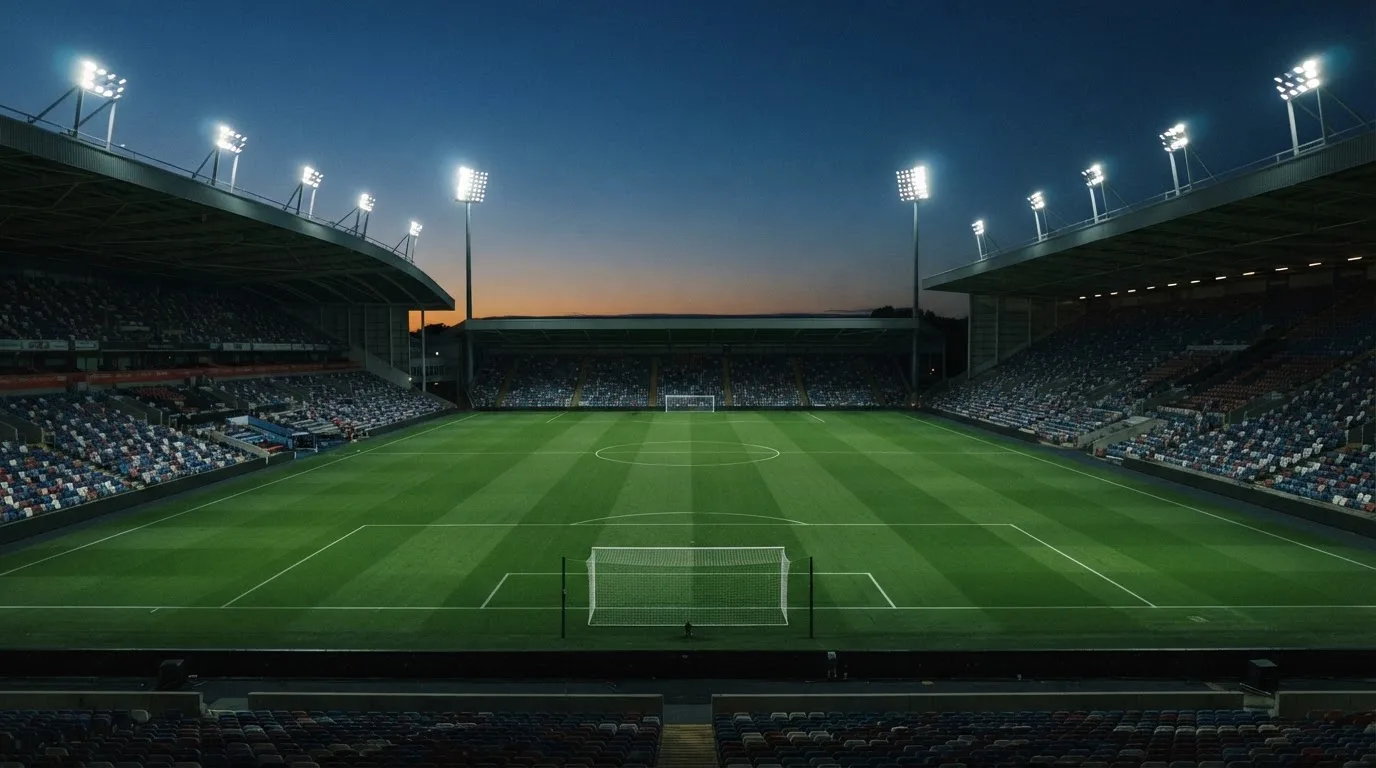 An empty football stadium with floodlight masts at dusk